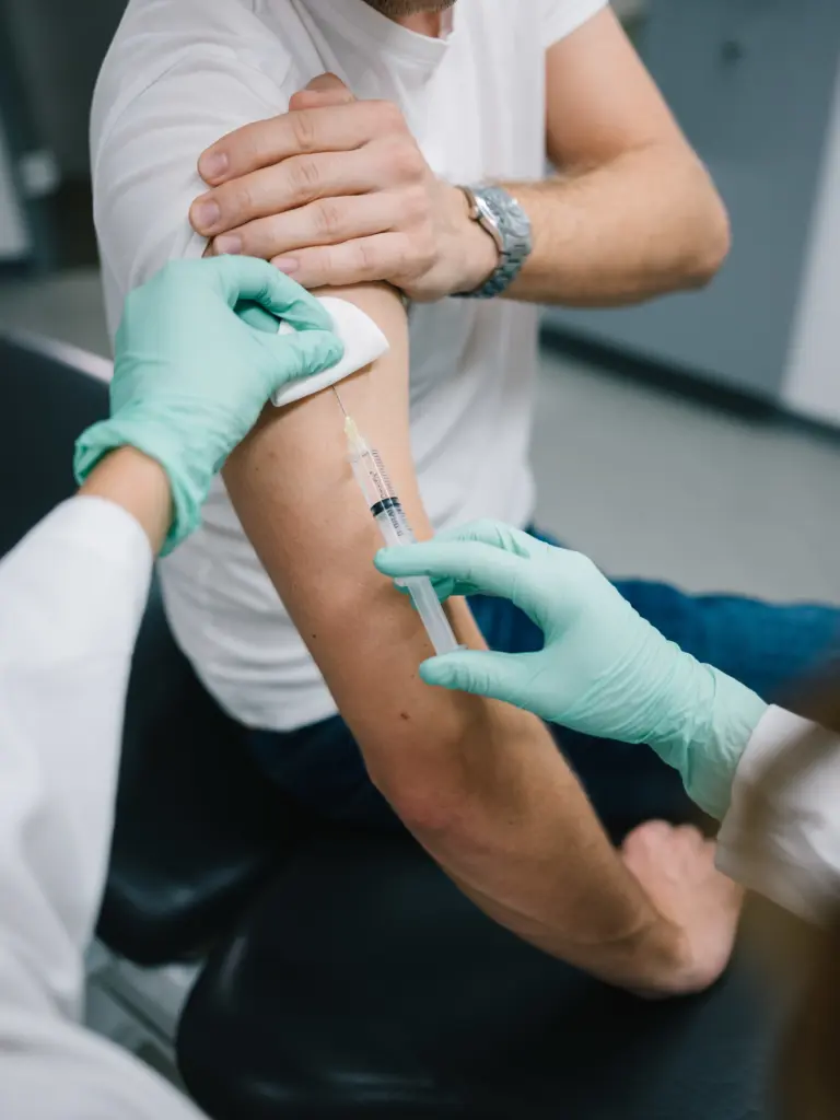 Hausarzt in München Neuhausen verabreicht Impfung im Arm eines Patienten, symbolisiert umfassende Impfberatung und Expertise.